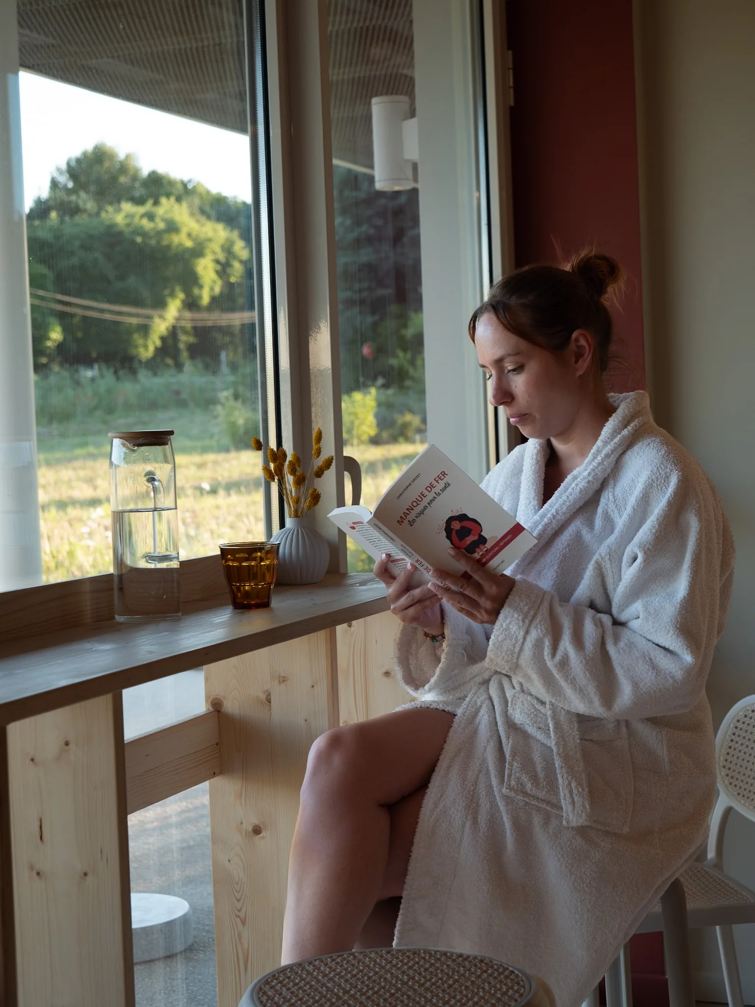 Une pause lecture en peignoir au café du club, près de la fenêtre