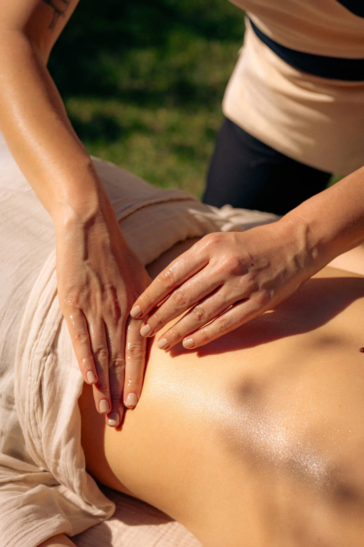 Les mains d’une praticienne réalisant un massage du dos à l’huile